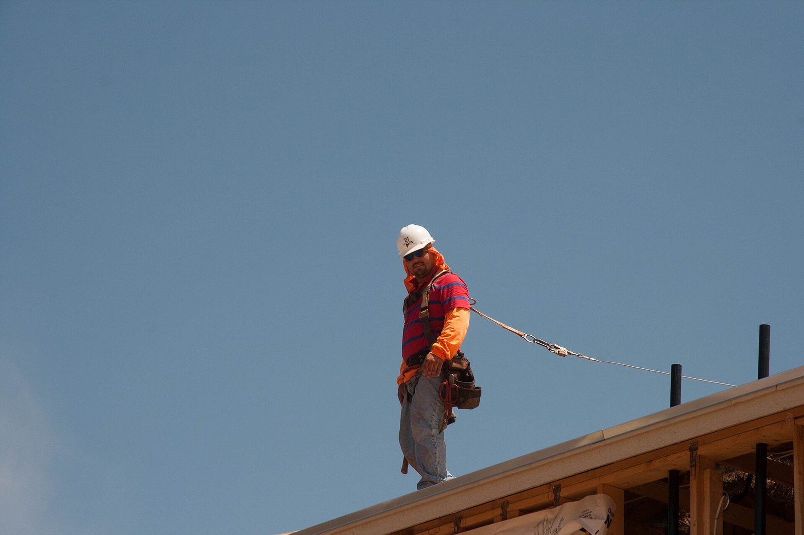Roofer tied off to a lifeline at the roof edge